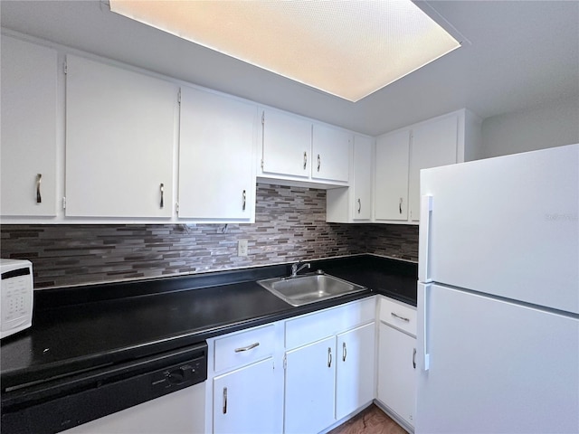 kitchen featuring white cabinetry, white appliances, dark countertops, and a sink