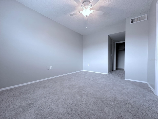 unfurnished bedroom with a textured ceiling, baseboards, carpet flooring, ceiling fan, and visible vents