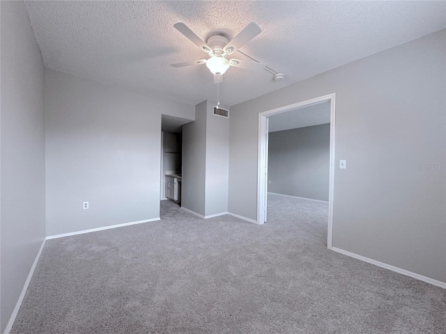 carpeted spare room with a textured ceiling, visible vents, baseboards, and ceiling fan