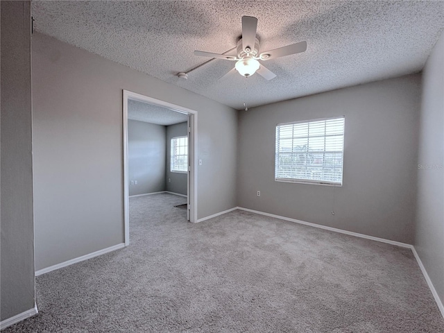 carpeted empty room with ceiling fan, a textured ceiling, and baseboards