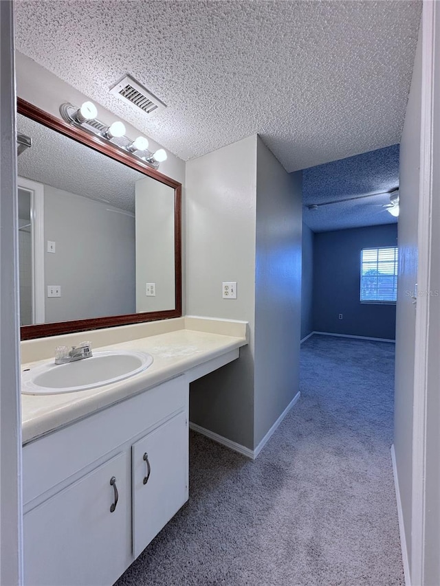 bathroom featuring vanity, a textured ceiling, baseboards, and visible vents