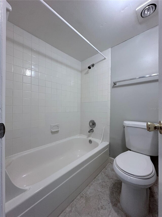 bathroom featuring toilet, shower / bath combination, and baseboards