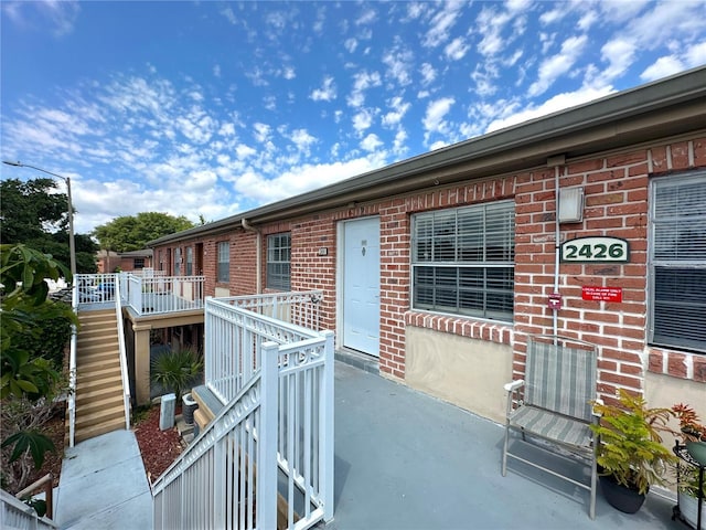 entrance to property featuring a wooden deck and brick siding