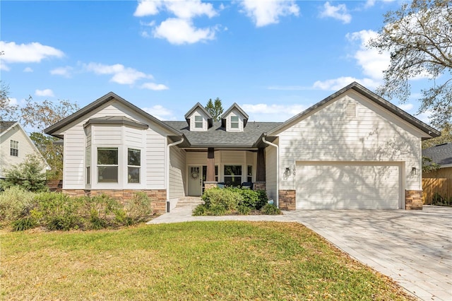 view of front facade featuring a front yard, a garage, decorative driveway, a shingled roof, and stone siding
