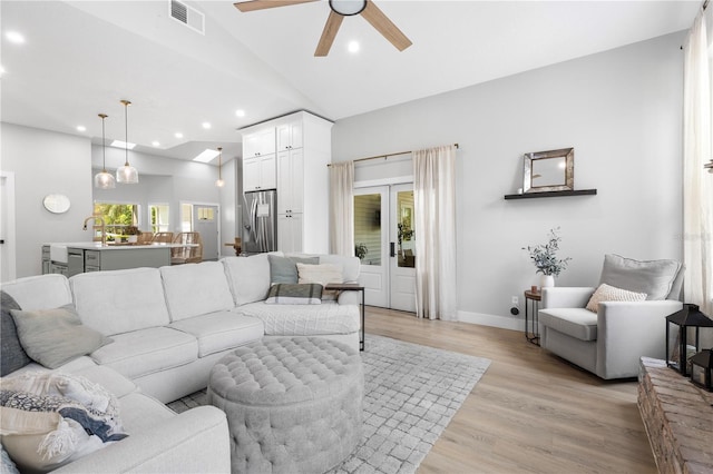 living room featuring a ceiling fan, visible vents, light wood-type flooring, lofted ceiling, and recessed lighting