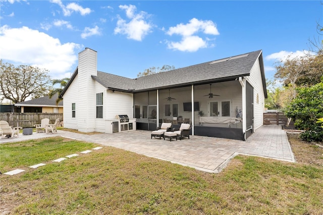 back of property with ceiling fan, fence, a patio area, a lawn, and an outdoor fire pit