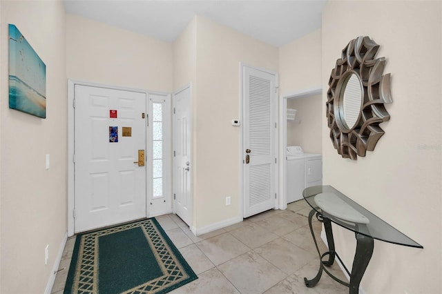 foyer with independent washer and dryer, light tile patterned flooring, and baseboards