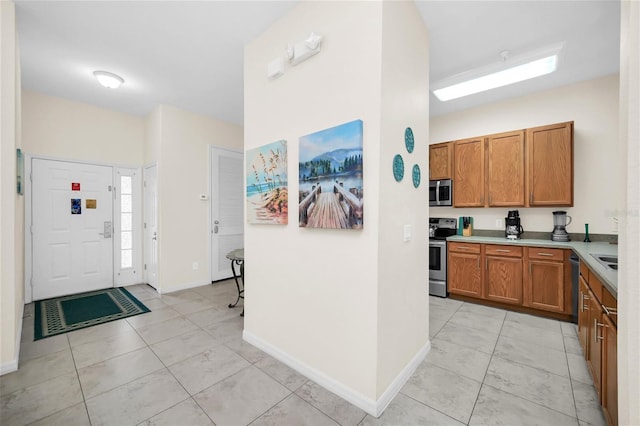 interior space featuring brown cabinetry, light countertops, baseboards, stainless steel appliances, and light tile patterned flooring