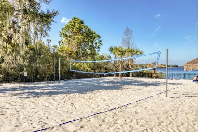 view of home's community with a water view, fence, and volleyball court