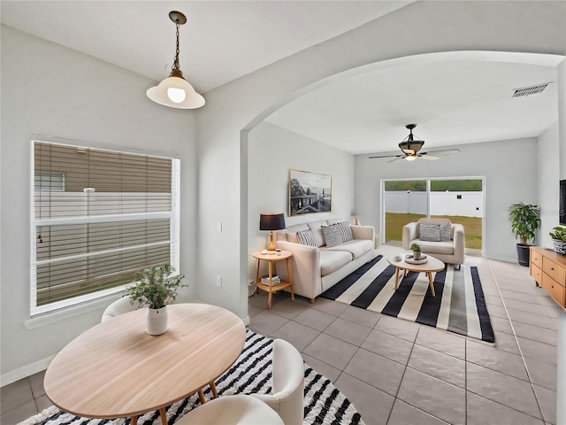 living area with a ceiling fan, visible vents, arched walkways, baseboards, and light tile patterned flooring