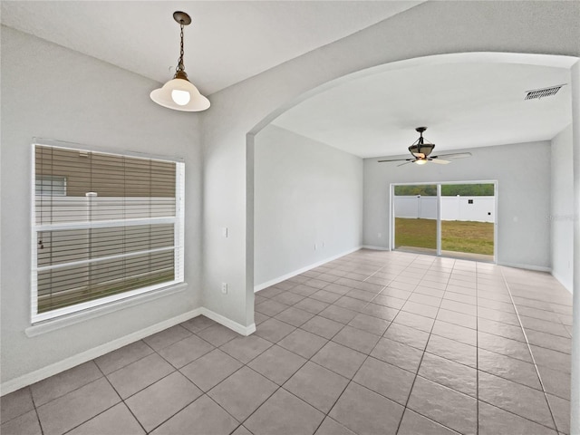 spare room featuring visible vents, tile patterned flooring, baseboards, ceiling fan, and arched walkways