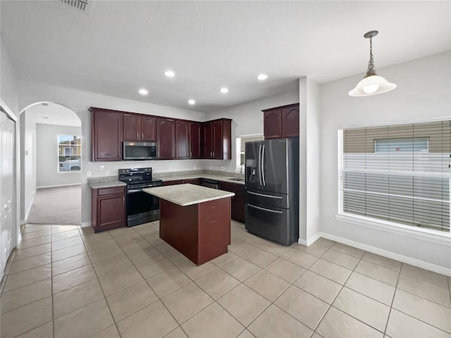 kitchen with a kitchen island, appliances with stainless steel finishes, arched walkways, light tile patterned floors, and baseboards