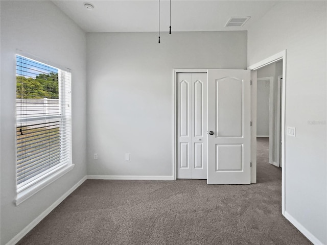 unfurnished bedroom with baseboards, carpet, a closet, and visible vents