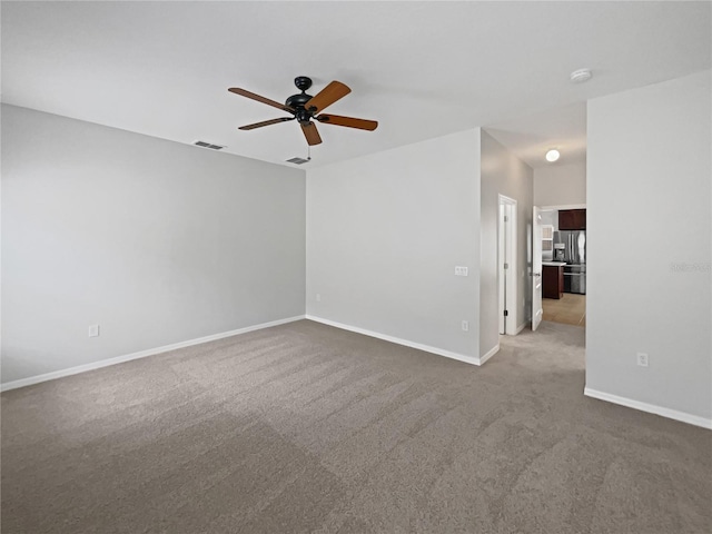 carpeted spare room featuring baseboards, a ceiling fan, and visible vents