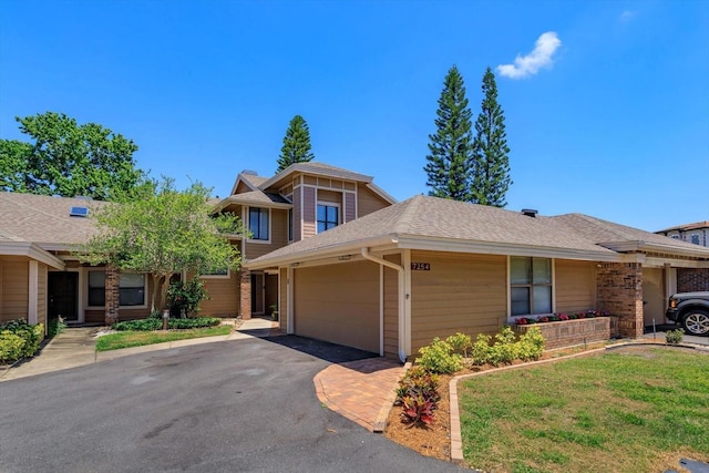 view of front facade with an attached garage, driveway, roof with shingles, and a front lawn