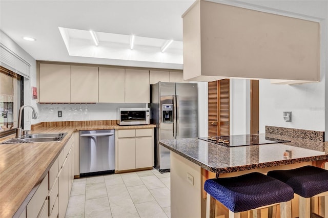311 Needles Trl, Longwood, FL 32779 - kitchen with stainless steel appliances, a sink, a peninsula, a breakfast bar, and dark stone countertops
