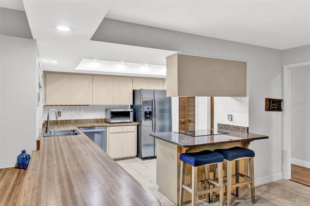 311 Needles Trl, Longwood, FL 32779 - kitchen with appliances with stainless steel finishes, a sink, a peninsula, a kitchen bar, and dark stone countertops