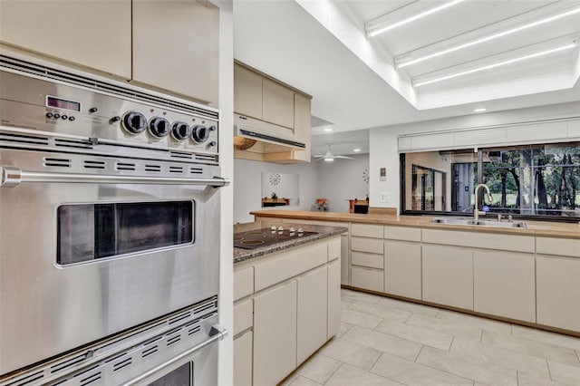 311 Needles Trl, Longwood, FL 32779 - kitchen with a sink, black electric stovetop, light tile patterned flooring, under cabinet range hood, and a ceiling fan