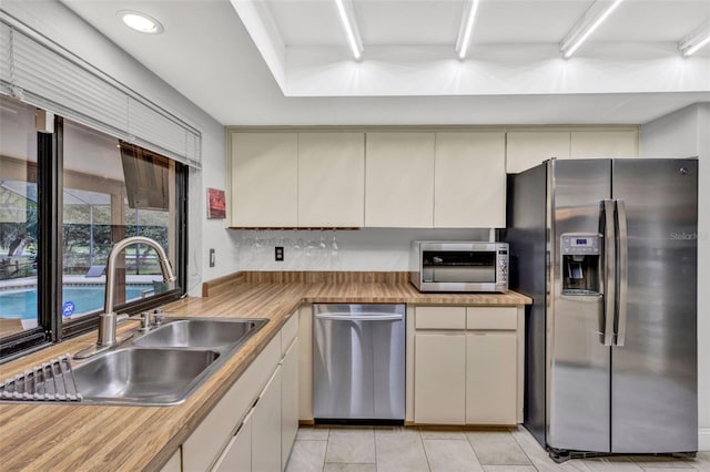 311 Needles Trl, Longwood, FL 32779 - kitchen featuring stainless steel appliances, a sink, cream cabinets, light tile patterned flooring, and recessed lighting