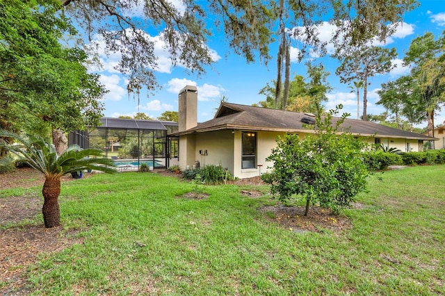 311 Needles Trl, Longwood, FL 32779 - rear view of property with a chimney, stucco siding, a lawn, and glass enclosure