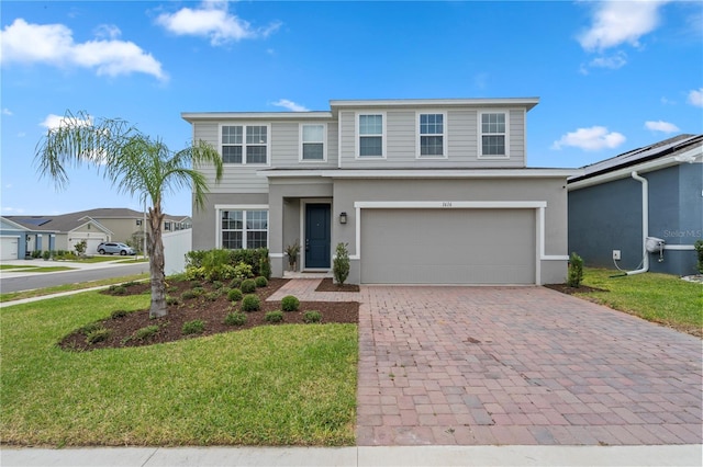 traditional home featuring an attached garage, stucco siding, a front lawn, and decorative driveway