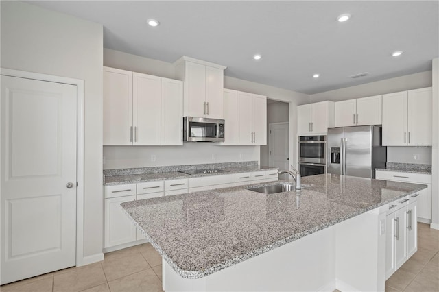 kitchen featuring stainless steel appliances, light tile patterned floors, an island with sink, and a sink
