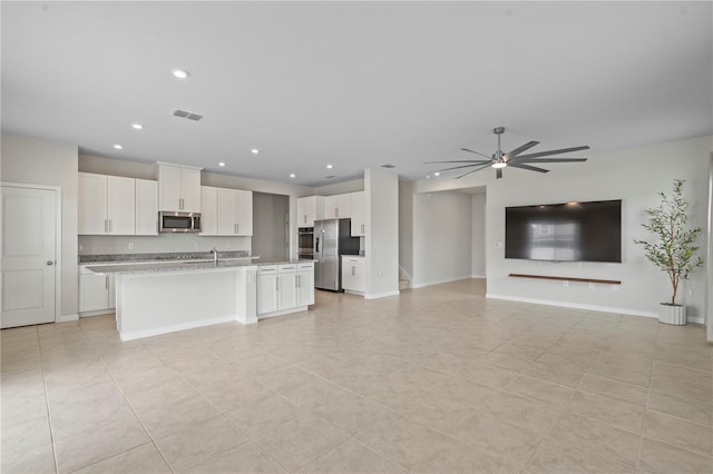 kitchen featuring a ceiling fan, appliances with stainless steel finishes, white cabinets, open floor plan, and light tile patterned flooring