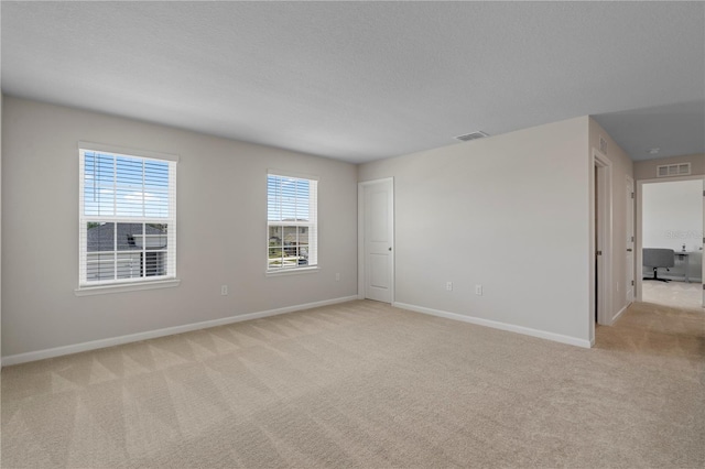 unfurnished room with light colored carpet, baseboards, and visible vents