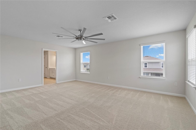 unfurnished room with a ceiling fan, baseboards, visible vents, and light carpet