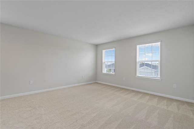 empty room with baseboards and light carpet