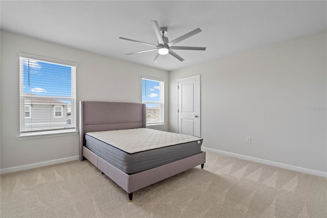 bedroom featuring light colored carpet, baseboards, and ceiling fan
