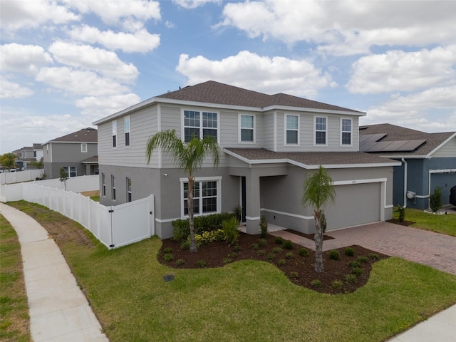 traditional-style house featuring fence, a shingled roof, a garage, a front yard, and driveway