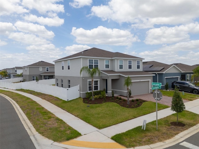 traditional home with a garage, fence, a front yard, a shingled roof, and driveway