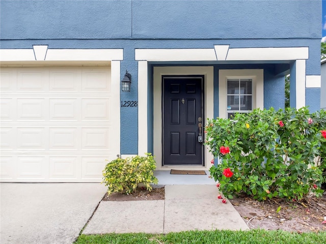 view of exterior entry with stucco siding and an attached garage