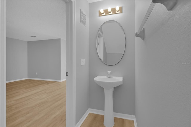 bathroom with a sink, baseboards, visible vents, and wood finished floors