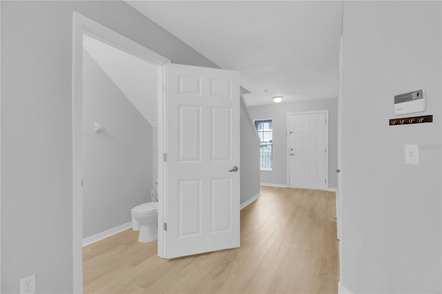 corridor with light wood-style flooring and baseboards