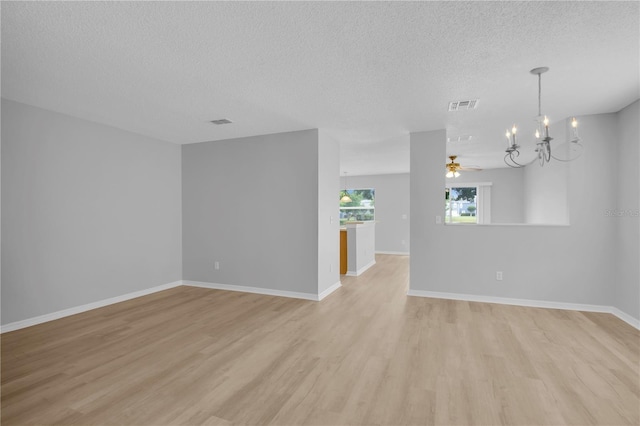 empty room featuring a textured ceiling, light wood-style floors, a chandelier, baseboards, and ceiling fan