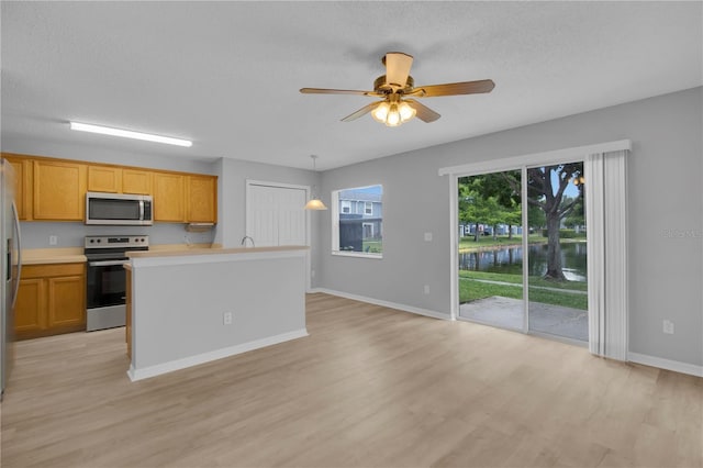 kitchen featuring stainless steel appliances, light wood finished floors, light countertops, a ceiling fan, and baseboards