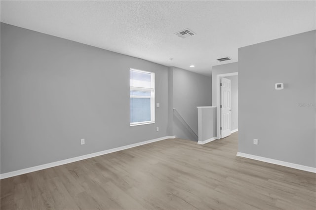 unfurnished room featuring wood finished floors, baseboards, a textured ceiling, and recessed lighting