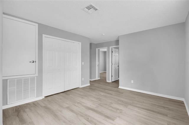 unfurnished bedroom featuring baseboards, a closet, visible vents, and wood finished floors