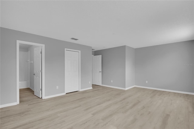 unfurnished bedroom with light wood-style flooring, baseboards, and a closet