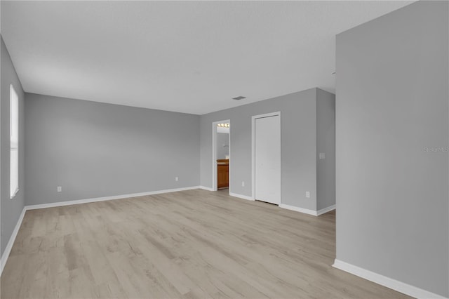 unfurnished room featuring baseboards, light wood-type flooring, and visible vents