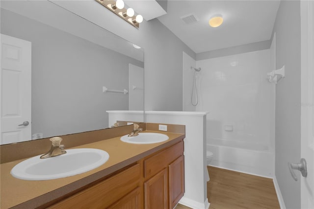 full bathroom featuring double vanity, toilet, wood finished floors, and shower / tub combination