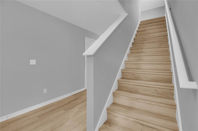 staircase with wood finished floors and baseboards