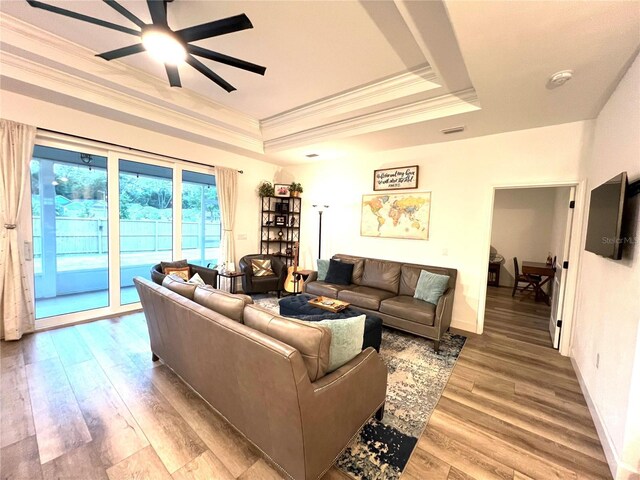 6709 SW 15th Pl, Gainesville, FL 32607 - living area featuring a tray ceiling, ceiling fan, crown molding, light wood-style floors, and baseboards