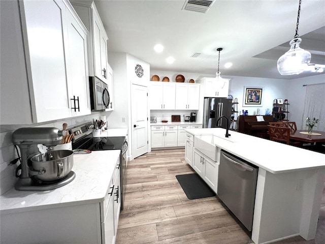 6709 SW 15th Pl, Gainesville, FL 32607 - kitchen with stainless steel appliances, a sink, light wood-type flooring, decorative light fixtures, and white cabinets