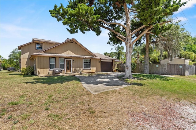 view of front of house with fence, driveway, a front yard, and a garage