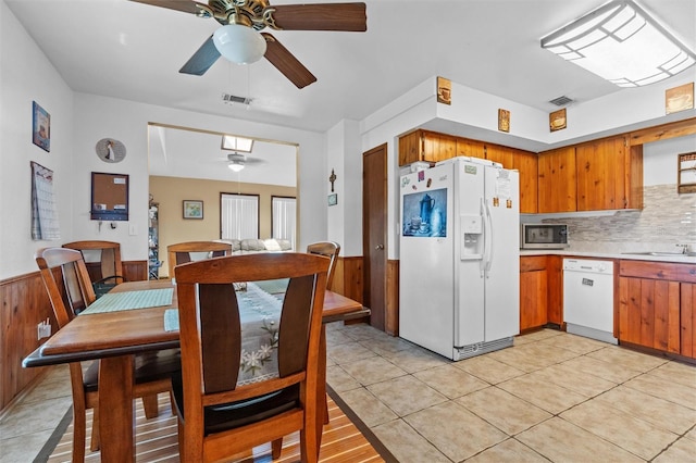 kitchen featuring wainscoting, light countertops, a ceiling fan, and white appliances