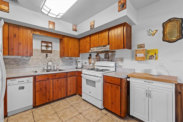 kitchen featuring a sink, white appliances, light countertops, tasteful backsplash, and under cabinet range hood