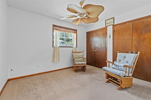 sitting room with carpet flooring, a ceiling fan, baseboards, and a textured ceiling